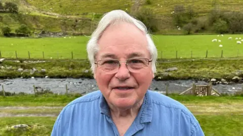 Robin Morris in a blue shirt near his home on the banks of the River Ystwyth in mid Wales.