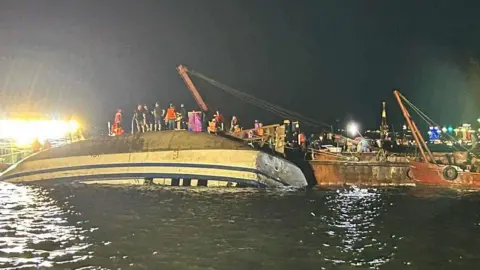 Getty Images Emergency services stand on top of a capsized tourist boat in Ha Long Bay, Quang Ninh province, Vietnam.