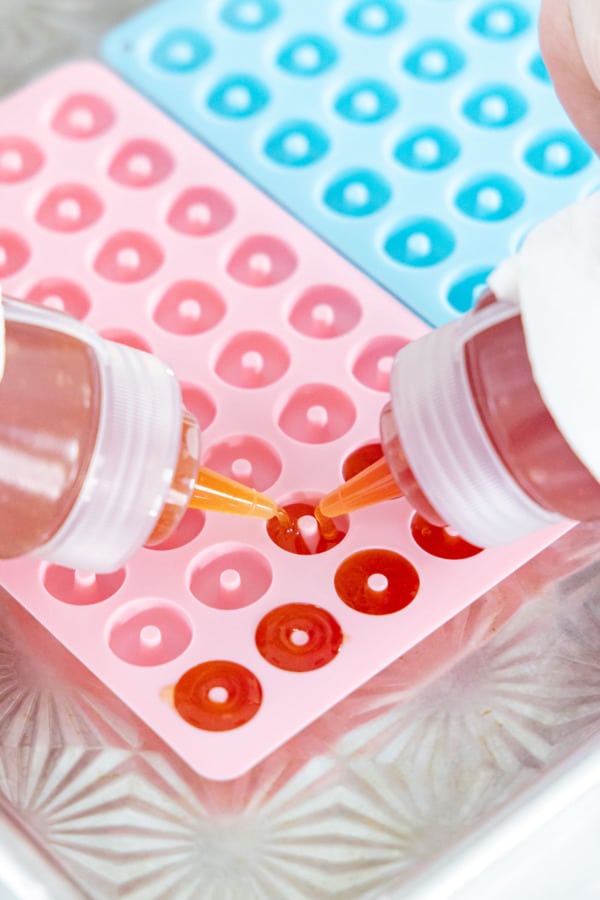 Squeezing two colors of liquid candy into the silicone molds to achieve the two-toned color effect.