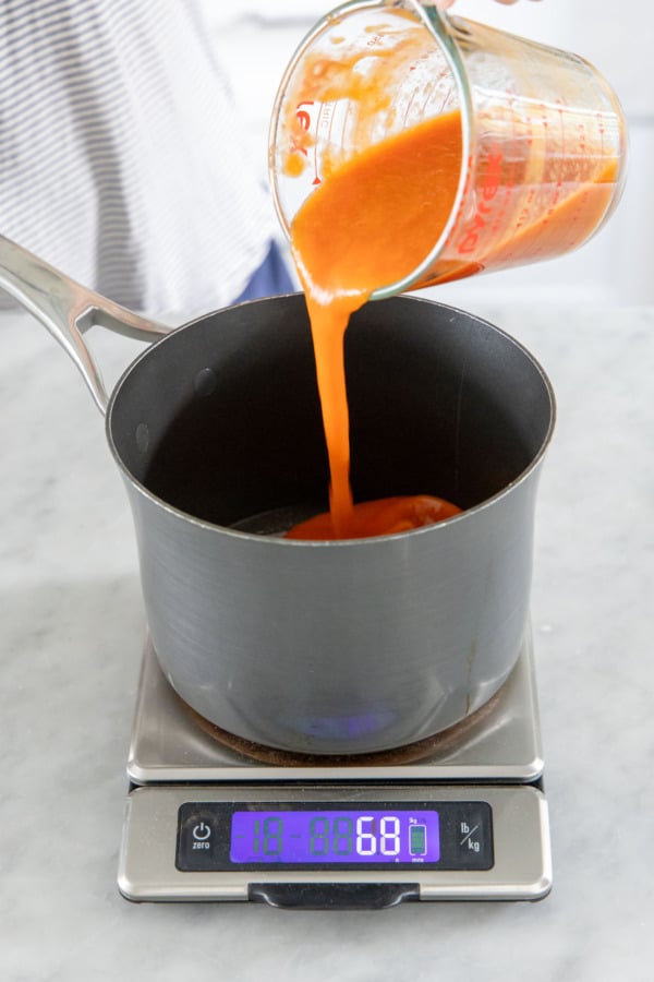 Pouring peach puree into the saucepan along with sugar and glucose.
