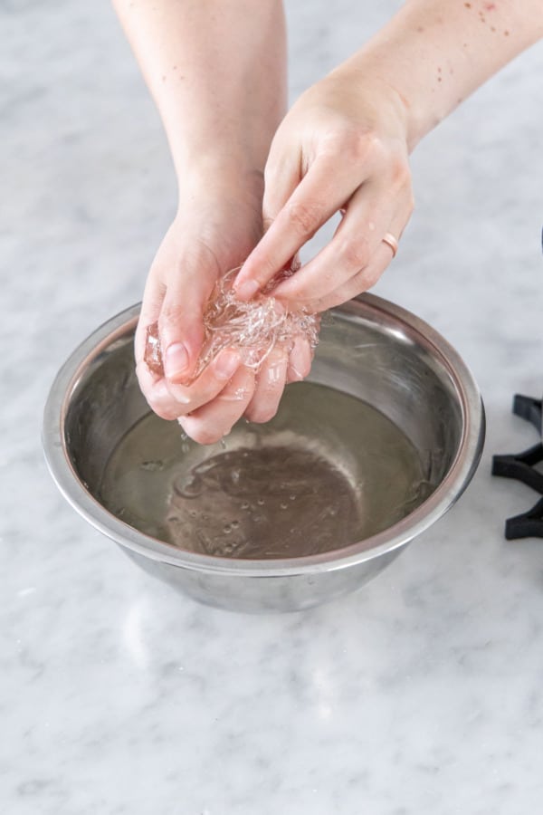 Squeezing softened gelatin to remove the excess water.