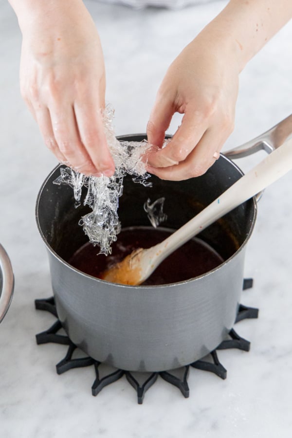 Adding softened gelatin to the hot liquid candy mixture.