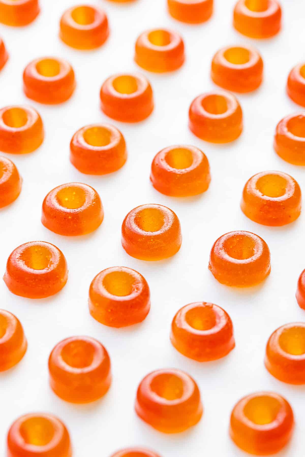 Rows of Homemade Gummy Peach Rings (made with Real Fruit and Gelatin) lined up like little soldiers on a parchment background.