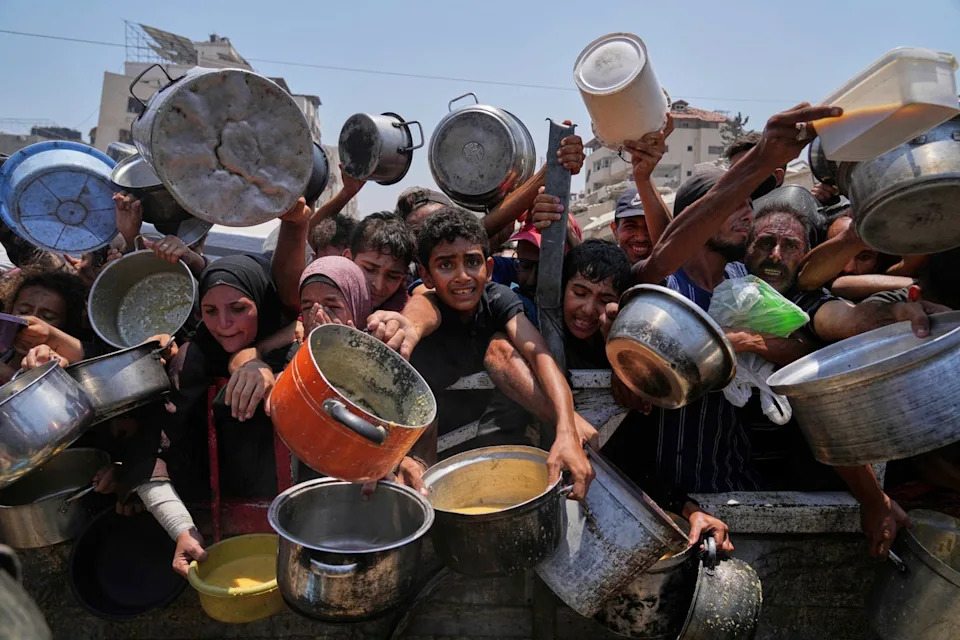 Palestinians struggle to get donated food at a community kitchen in Gaza City, northern Gaza Strip (AP)