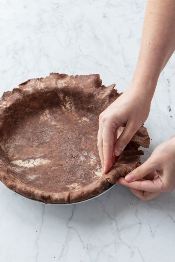 Folding the overhang under the edge of the pie crust.